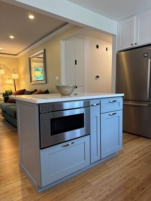 A modern kitchen with a built-in oven, a stainless steel refrigerator, and a light blue cabinetry. - Cozy 3 bed Craftsman Retreat, 10 Min from the Big House (Ann Arbor)