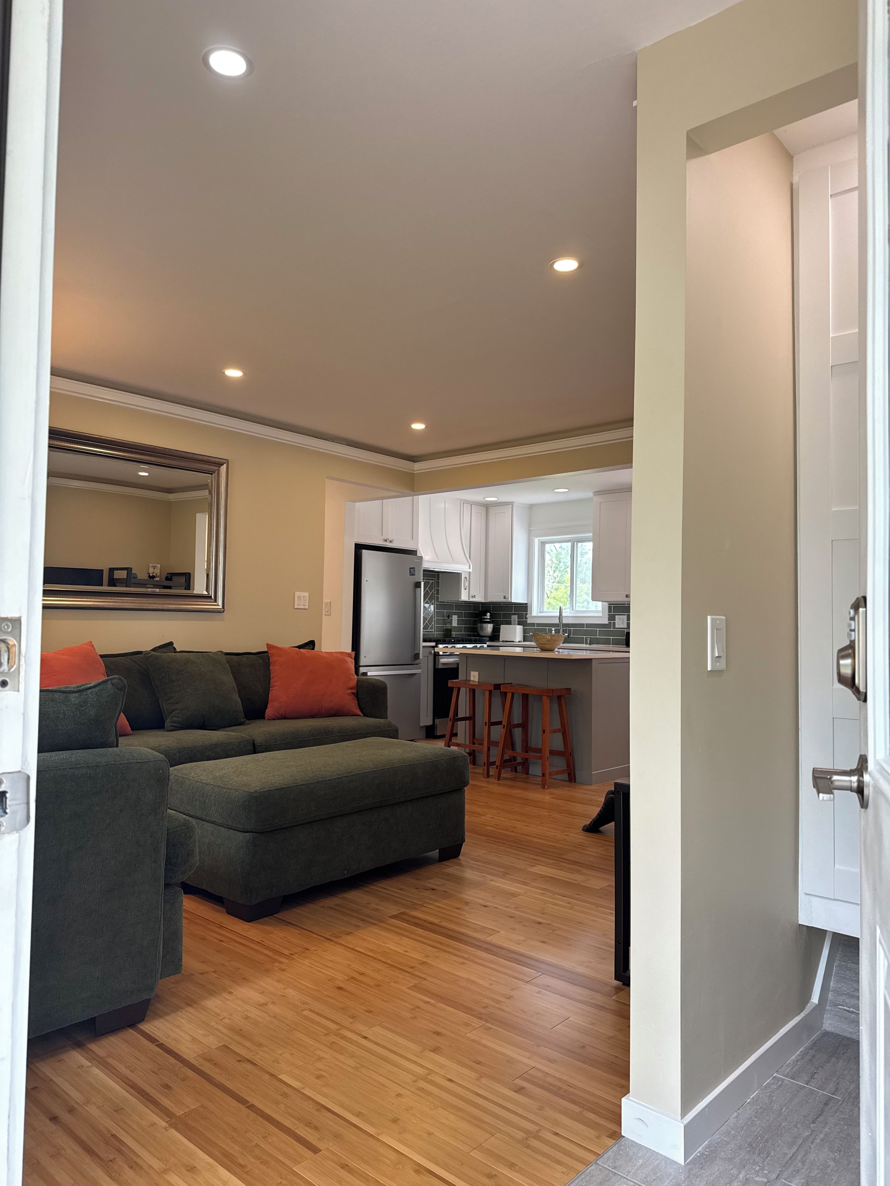 A modern kitchen with a refrigerator, stove, and bar stools.