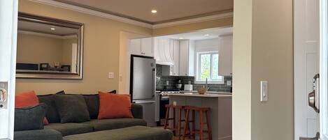 A modern kitchen with a refrigerator, stove, and bar stools.