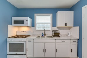 A compact kitchen with white cabinetry, a microwave, stove, and a sink. - Near Texans | NRG Stadium | Med Center | Downtown! (Houston)