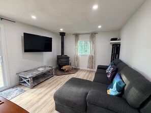 A modern living room with a sofa, a flat-screen TV, a fireplace, and a window with curtains.