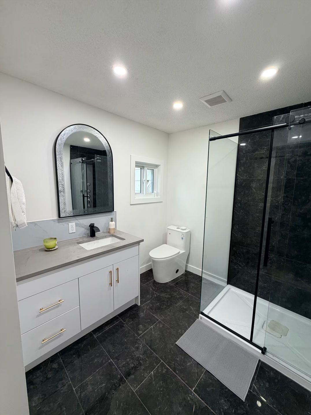 Een moderne badkamer met een douchecabine van glas, een toilet en een wastafel met spiegel.