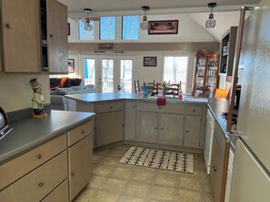 A kitchen with a central island, wooden cabinets, a built-in oven, and a view of the outdoors through large windows.
