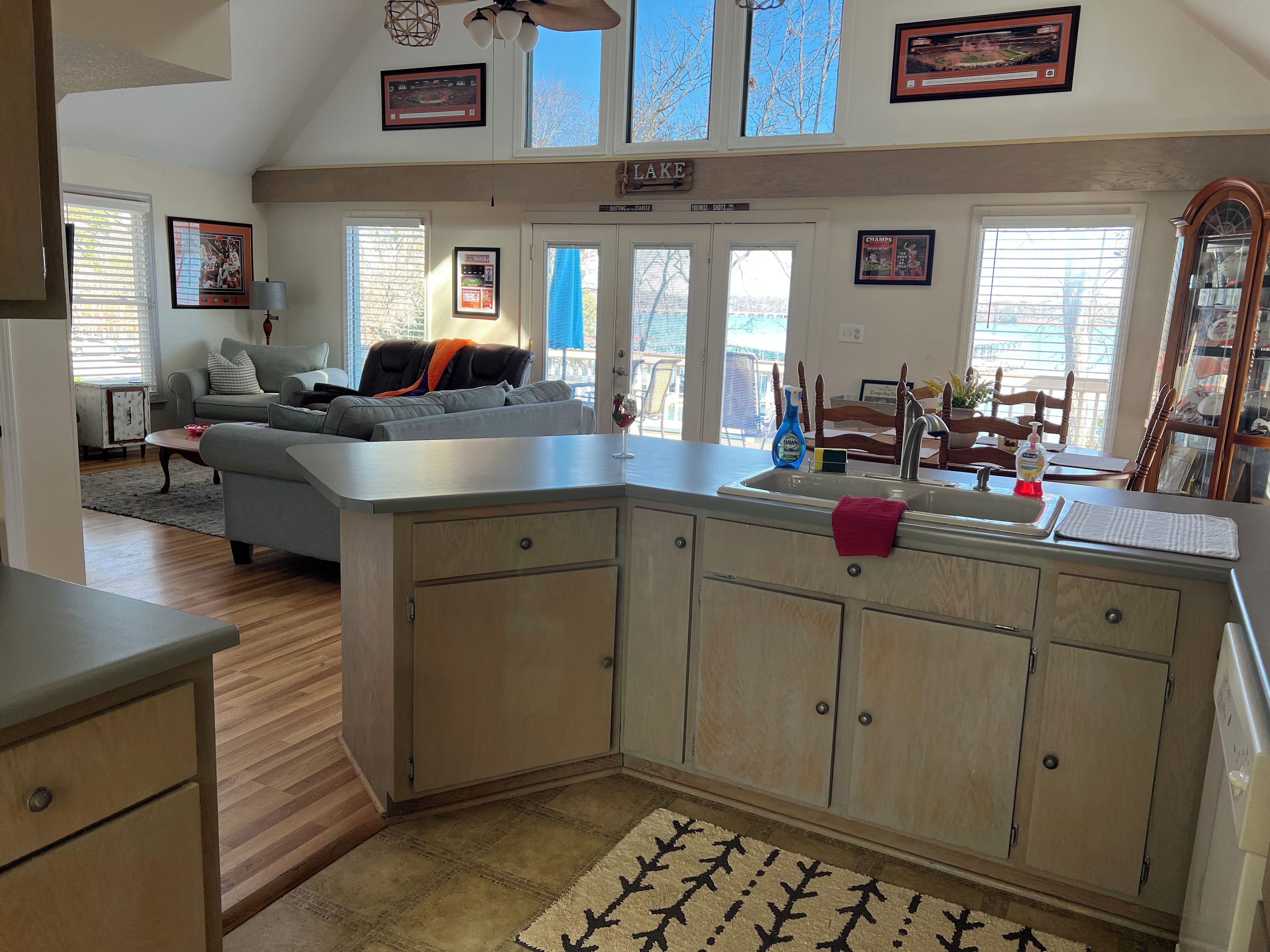 Una cocina con una isla grande, un comedor con mesa y sillas, y una sala de estar con sofá y sillón.