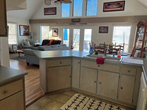 A kitchen with a large island, a dining area with a table and chairs, and a living room with a sofa and a chair.