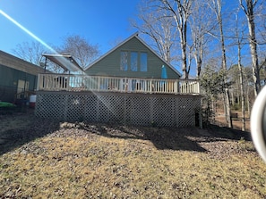 A house with a deck, a fenced yard, and leaf-covered ground.