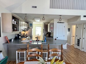 A modern kitchen with a central island, wooden chairs, and a dining table.
