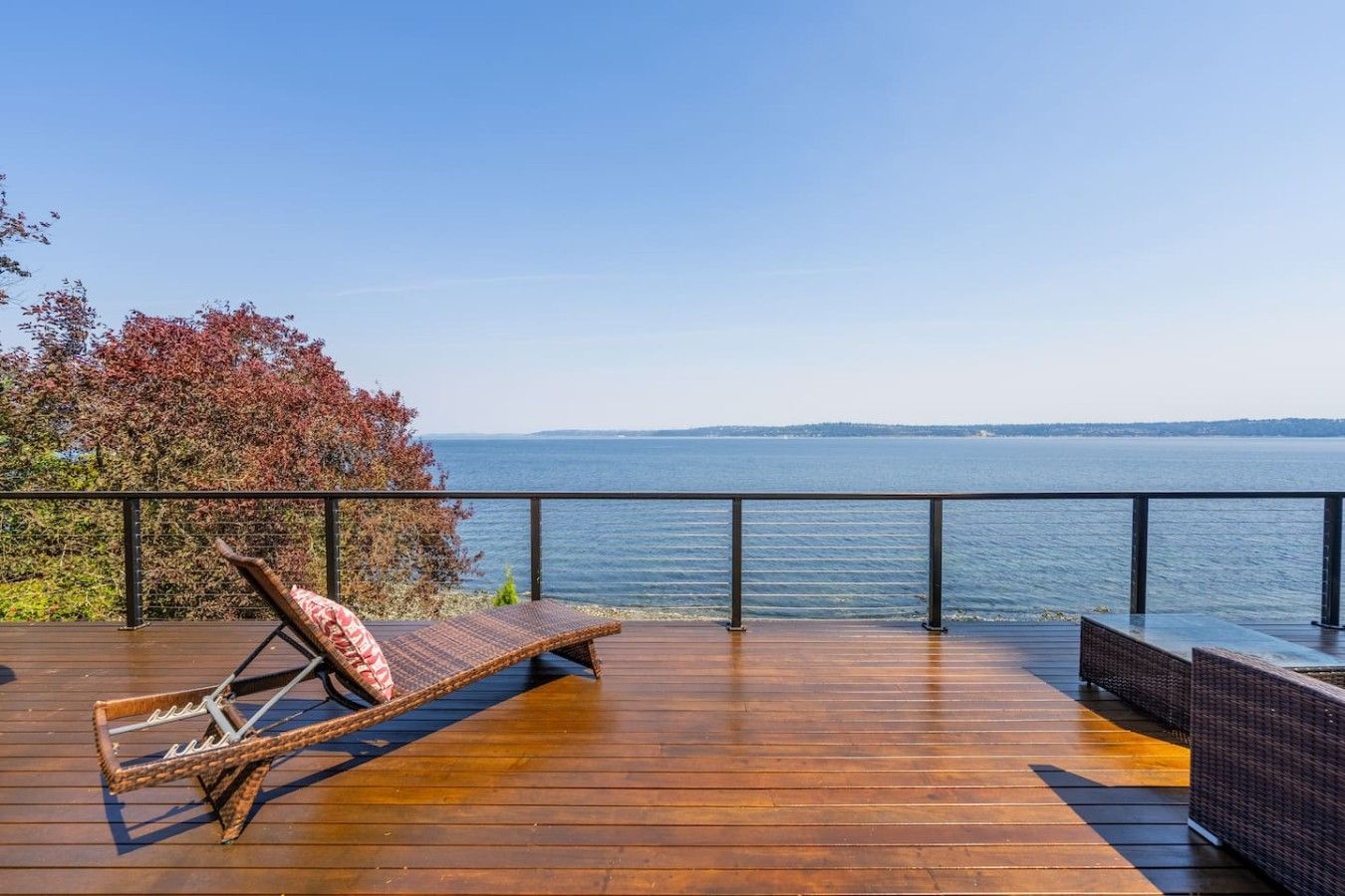 Un terrazzo in legno con una sedia a sdraio e vista sul mare.