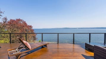 Un terrazzo in legno con una sedia a sdraio e vista sul mare.