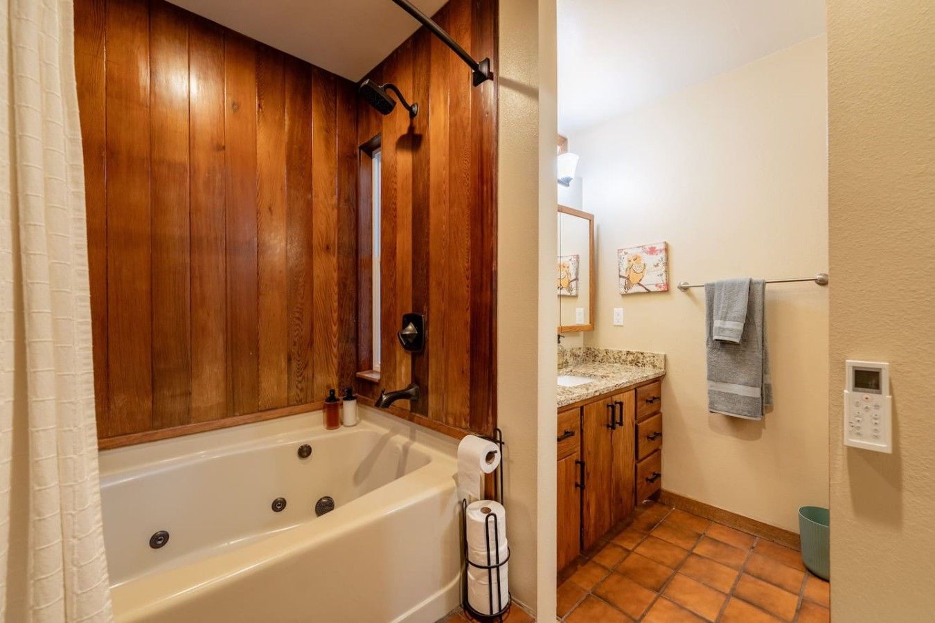 A bathroom with a wooden panel wall, a bathtub, a shower, a sink with a countertop, and a towel rack.