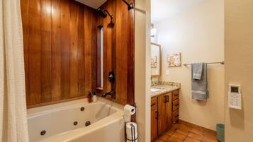 A bathroom with a wooden panel wall, a bathtub, a shower, a sink with a countertop, and a towel rack.