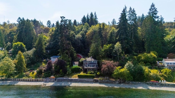 Une propriété située au bord de l’eau, avec une maison entourée d’une forêt dense, un quai et une vue dégagée sur l’eau.
