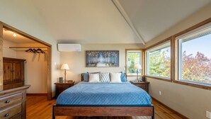 Une chambre à coucher avec un lit en bois, une table de chevet avec une lampe, une commode et un tableau accroché au mur.