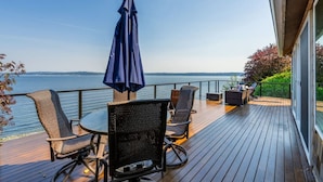 Une terrasse dotée de mobilier d’extérieur, d’une table et d’un parasol, offrant une vue sur une étendue d’eau.