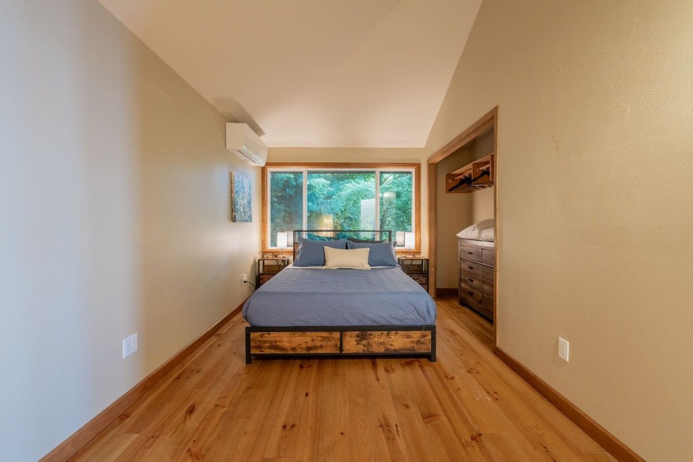 Una habitación estrecha con cama, ventana y cómoda.