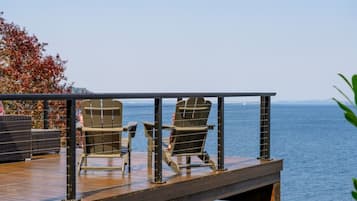 A deck with two Adirondack chairs facing a body of water.