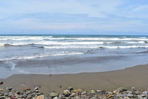 Una playa con olas, piedras y cielo despejado.