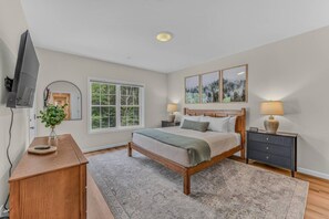 A bedroom with a bed, bedside tables, a TV, a window, and a painting. - Soulful Summit at Forest Ridge- Pools & Hot Tub (Lincoln)
