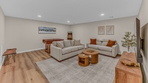 A modern living room with a sofa set, a coffee table, a small side table, and a foosball table. - Soulful Summit at Forest Ridge- Pools & Hot Tub (Lincoln)