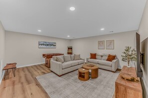 A modern living room with a sofa set, a coffee table, a small side table, and a foosball table. - Soulful Summit at Forest Ridge- Pools & Hot Tub (Lincoln)