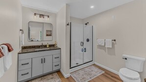 A bathroom with a shower, toilet, and vanity with a mirror. - Soulful Summit at Forest Ridge- Pools & Hot Tub (Lincoln)