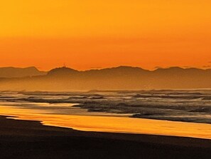 Uma praia com ondas e uma colina ao longe.