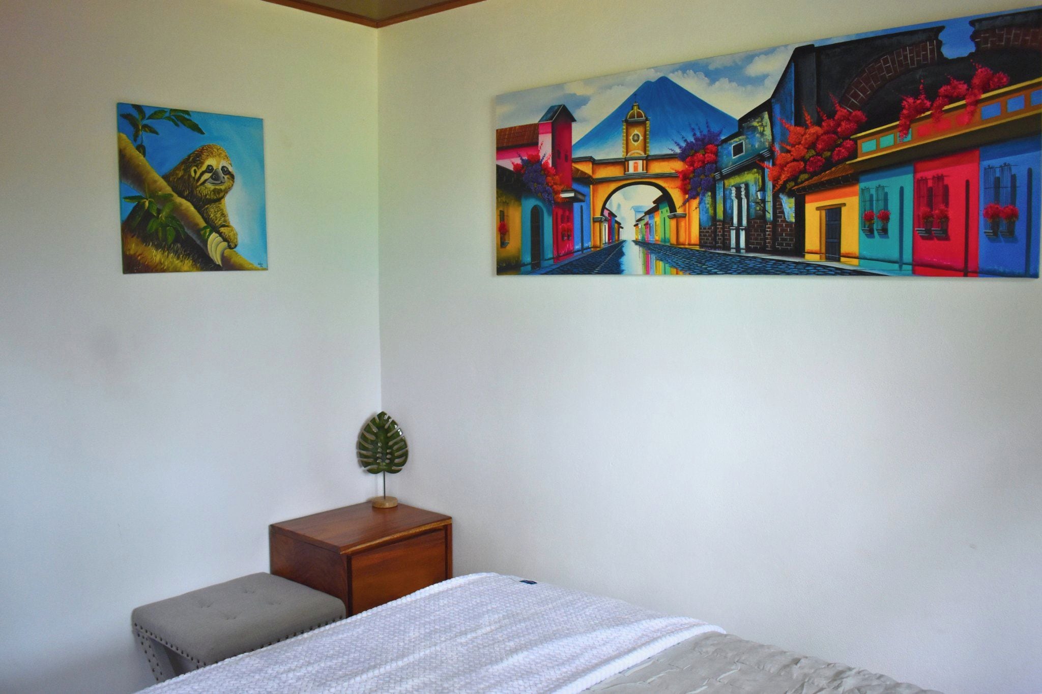 Un dormitorio con una cama, una mesita de noche y dos cuadros en la pared.