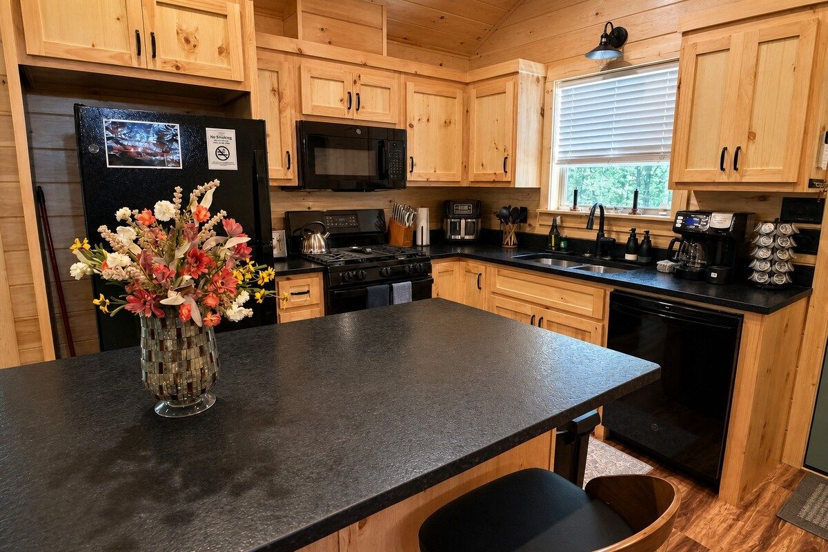 A kitchen with wooden cabinets, a black refrigerator, a microwave, a stove, and a sink.