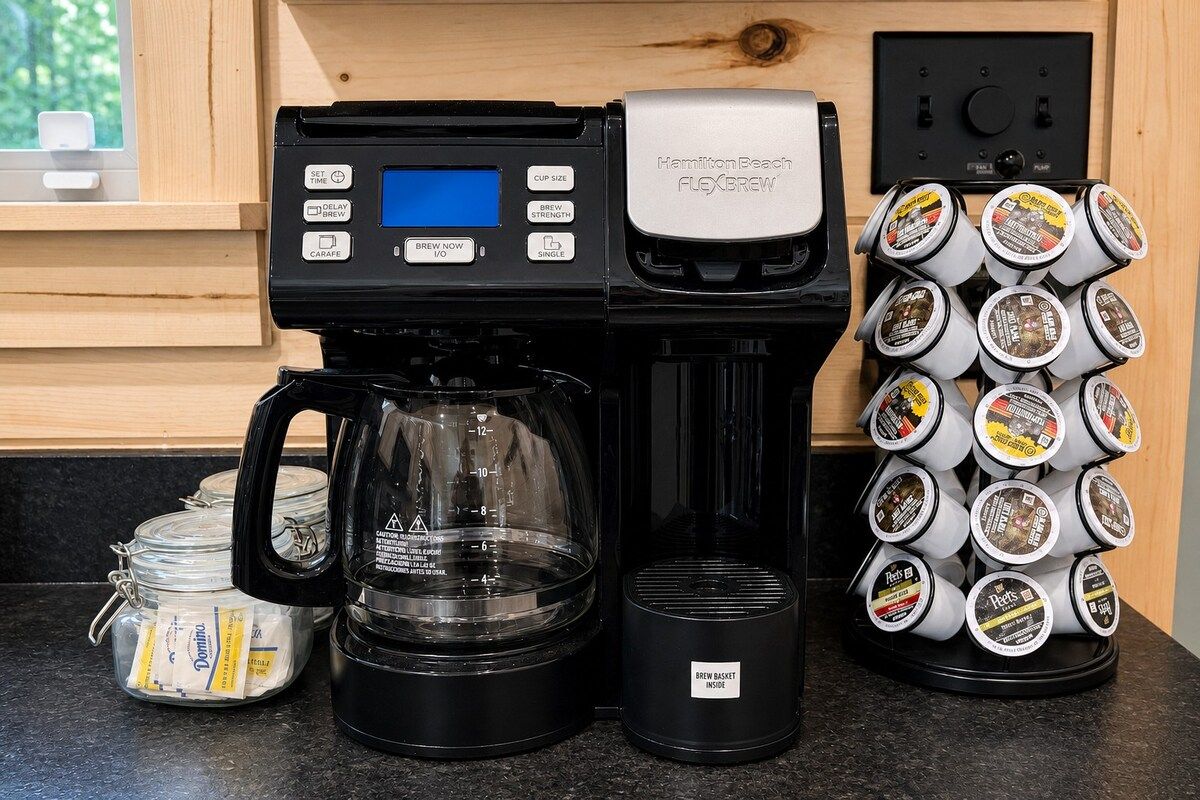 A coffee maker with a digital display, a coffee pot, and a coffee bean dispenser.