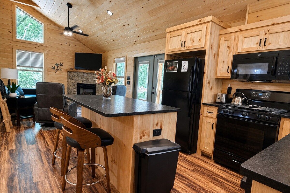 A spacious kitchen with wooden cabinets, a black refrigerator, a microwave, and a stove.