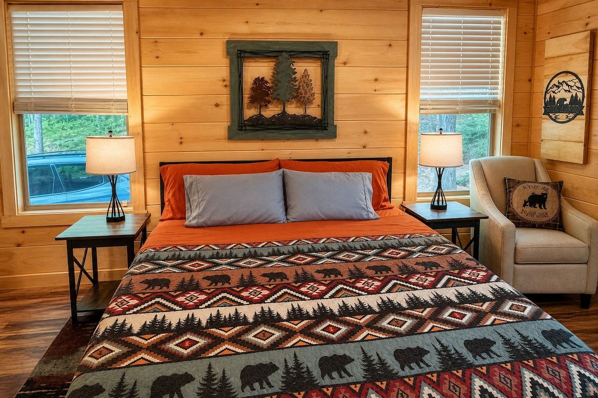A cozy bedroom with a bed, two nightstands, a chair, and a window with blinds.