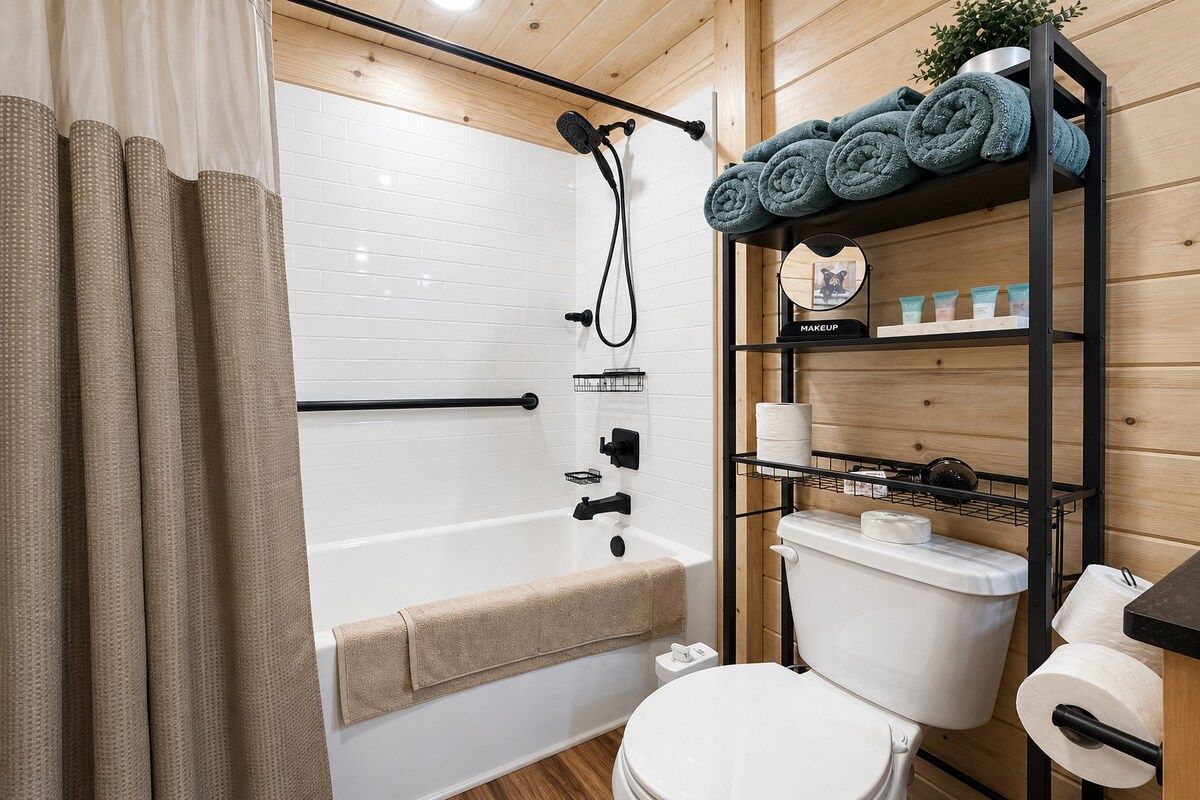 A bathroom with a shower, toilet, and shelves with towels and toiletries.