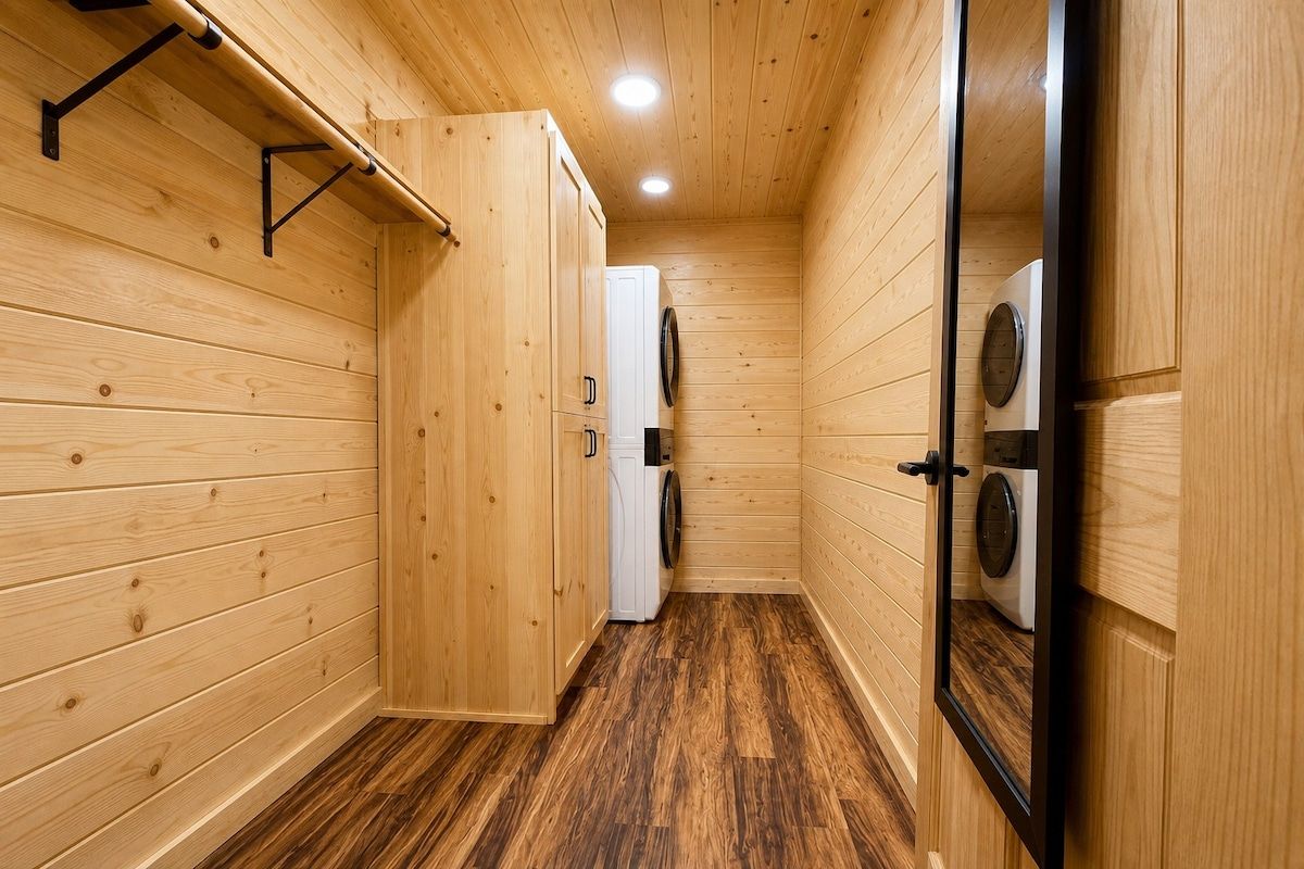 A wooden interior with a laundry area, including a washing machine and dryer.