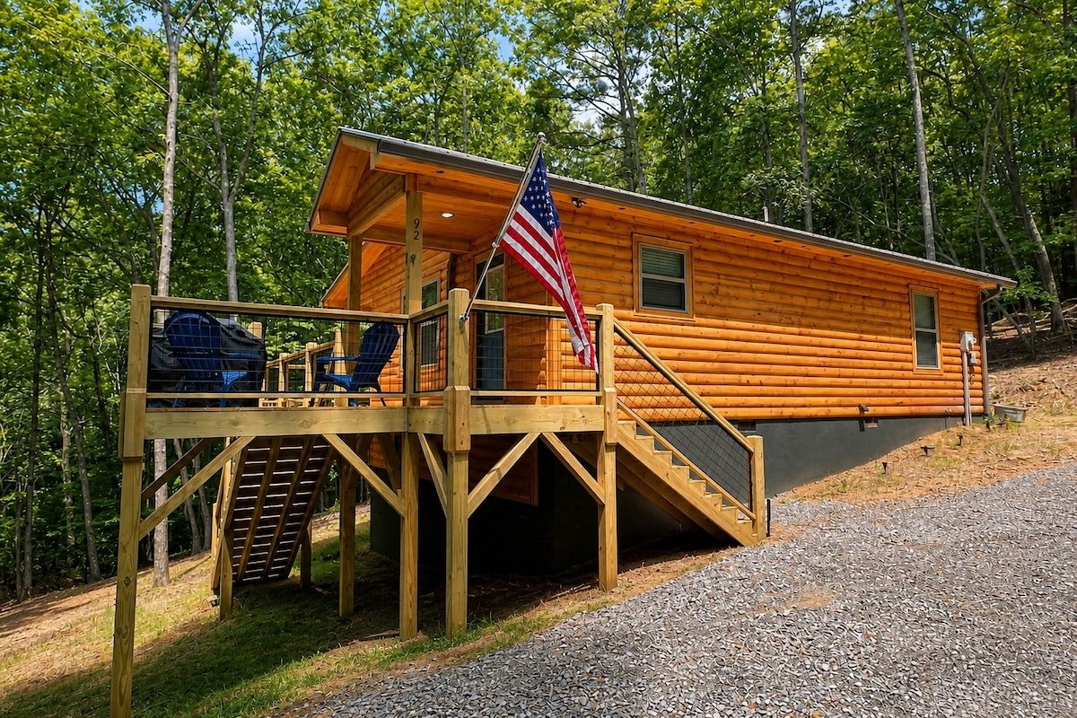 A cabin with a wooden deck, a staircase, and an American flag.