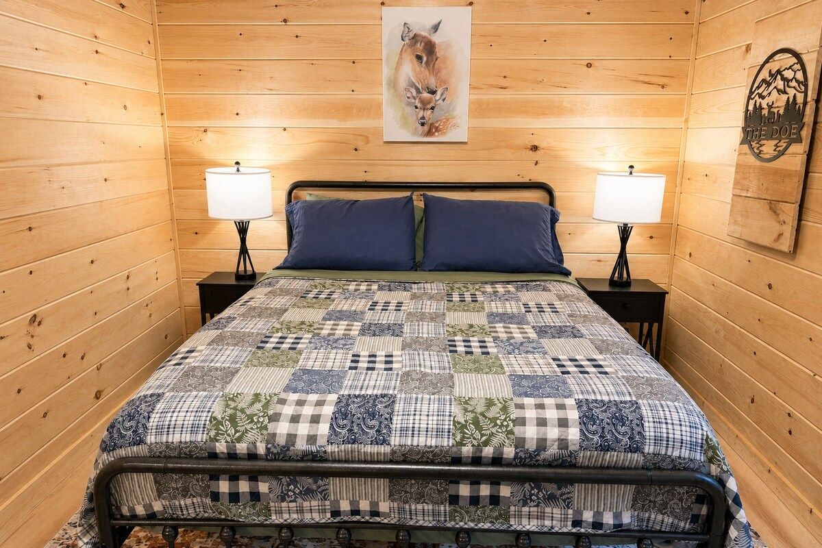 A wooden-paneled room with a bed, two bedside lamps, and a framed picture on the wall.