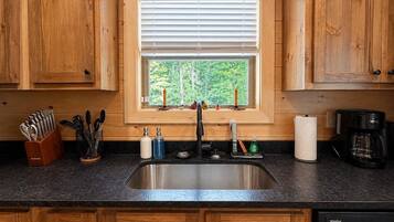 A kitchen with wooden cabinets, a stainless steel sink, and a window with blinds.