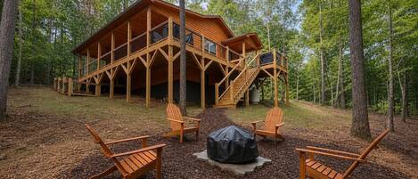 A wooden cabin with a deck and stairs, surrounded by trees.