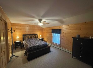 A bedroom with a bed, a dresser, a window with blinds, a ceiling fan, and a coat rack. - Pet friendly ski chalet 5min from Sunday River (Bethel)