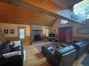 A cozy living room with a fireplace, leather sofas, and a TV. - Pet friendly ski chalet 5min from Sunday River (Bethel)