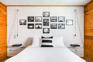A bedroom with a bed, white walls, wooden paneling, and a series of framed pictures on the wall. - The Pine Haven - 8 Min to Kalahari - Hot Tub & Fire Pit (Long Pond)