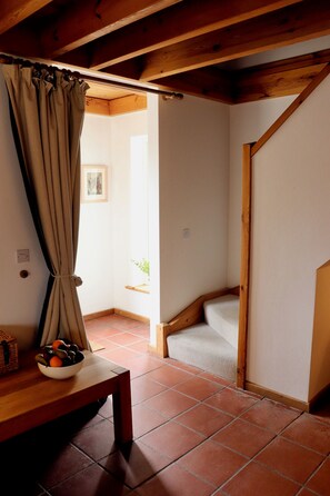 A room with a wooden ceiling, a window with curtains, a small table with a bowl of fruit, and a bench. - Waterville Holiday Home (Kerry)