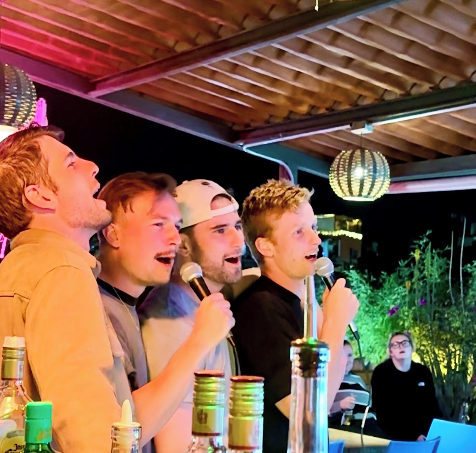 A group of people singing outdoors at night.