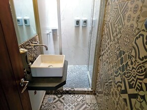 Un baño con lavamanos blanco, un espejo y baldosas con diseño.