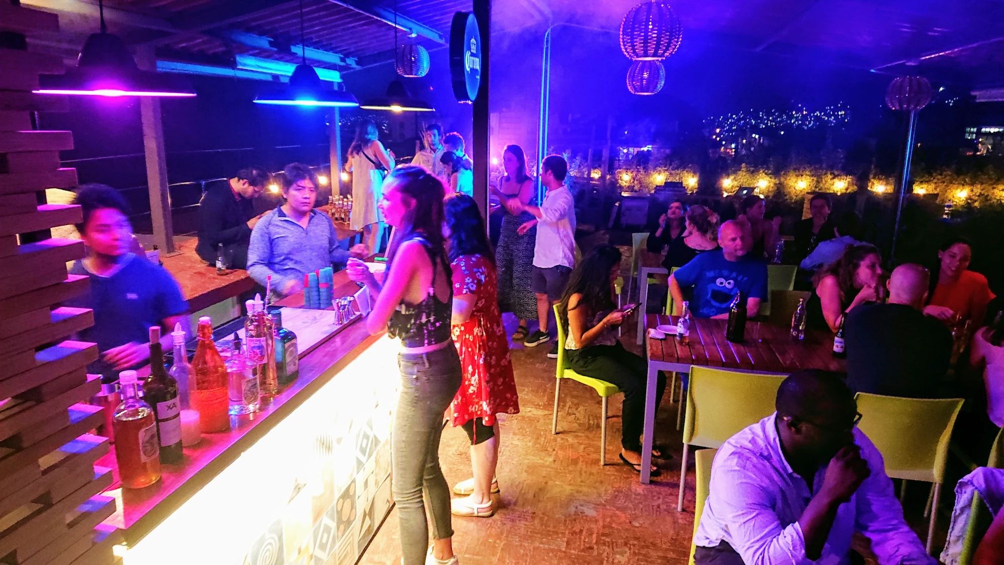 A crowded bar with a counter and stools, surrounded by people.