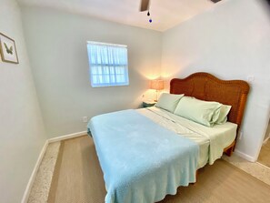 A bedroom with a bed, a nightstand, a lamp, a window, and a ceiling fan.