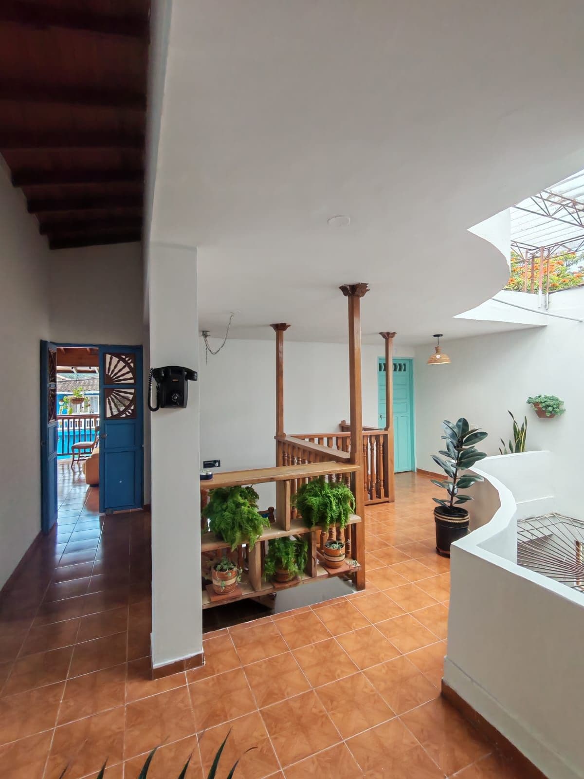 A spacious interior with a tiled floor, a wooden staircase, and a balcony with a view.