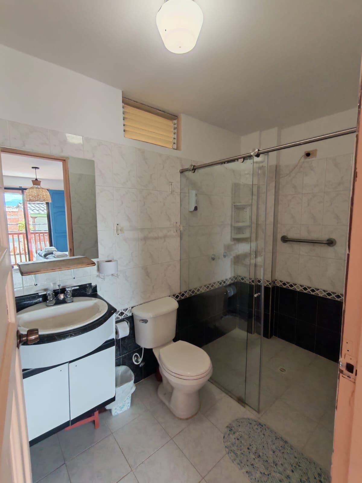 A bathroom with a toilet, sink, and shower area.