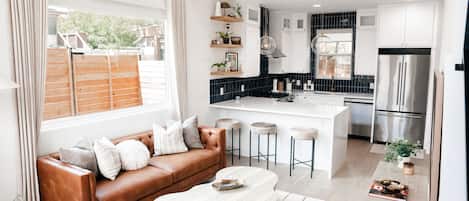 A modern kitchen with white cabinets, a stainless steel refrigerator, and a central island.