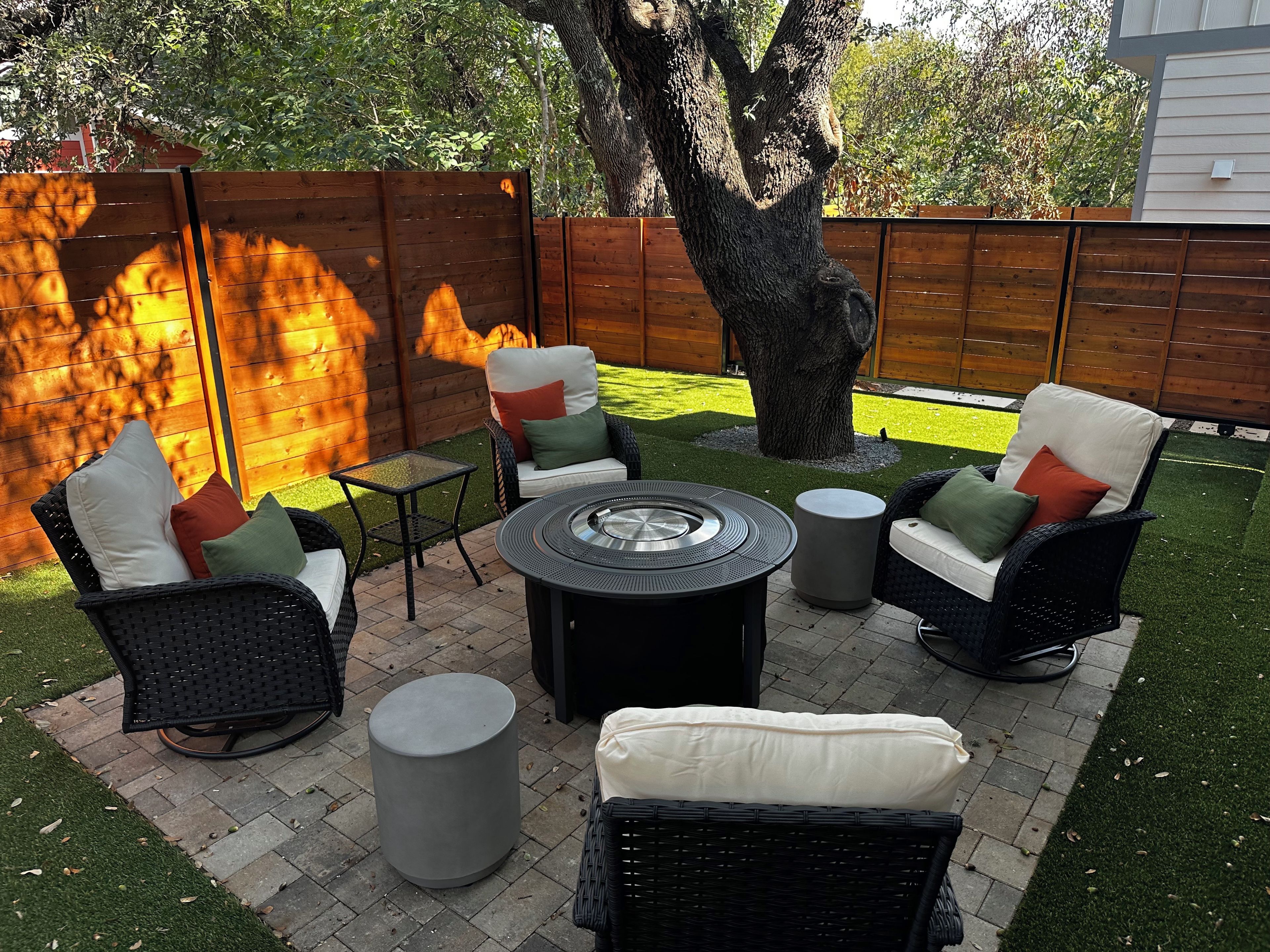 An outdoor patio area with wicker furniture, a round table, and a small fire pit.