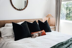 A bed with white bedding, black and white pillows, and a patterned throw. - Newly remodeled 2br/2ba on South First! OleMiss + F1! (Austin)